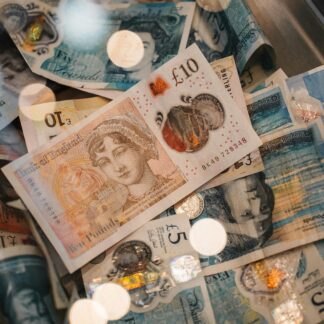 A detailed view of British £5 and £10 pound sterling notes with coins, featuring warm bokeh effects.